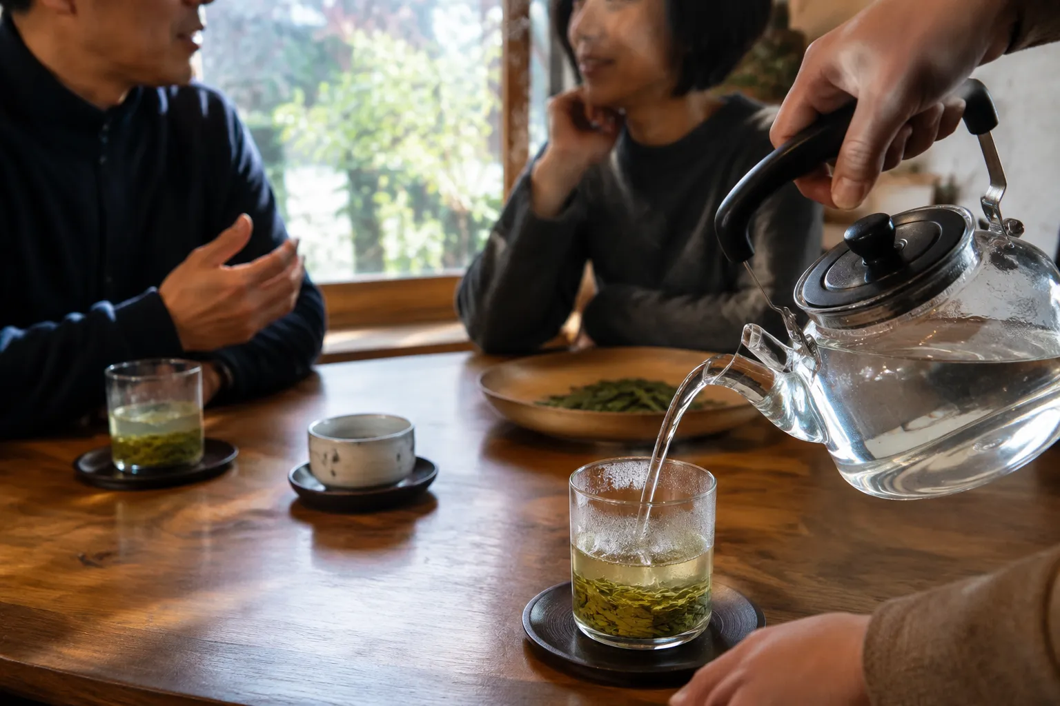A Longjing guest cup being refilled over the same visible leaves during conversation