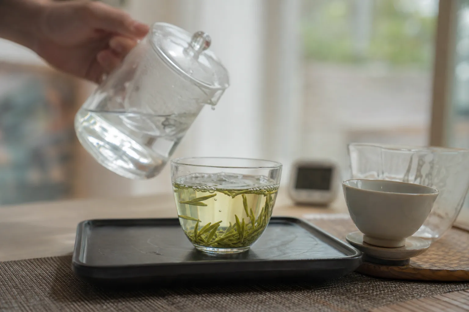 Longjing leaves opening in a clear glass cup during gentle guest service