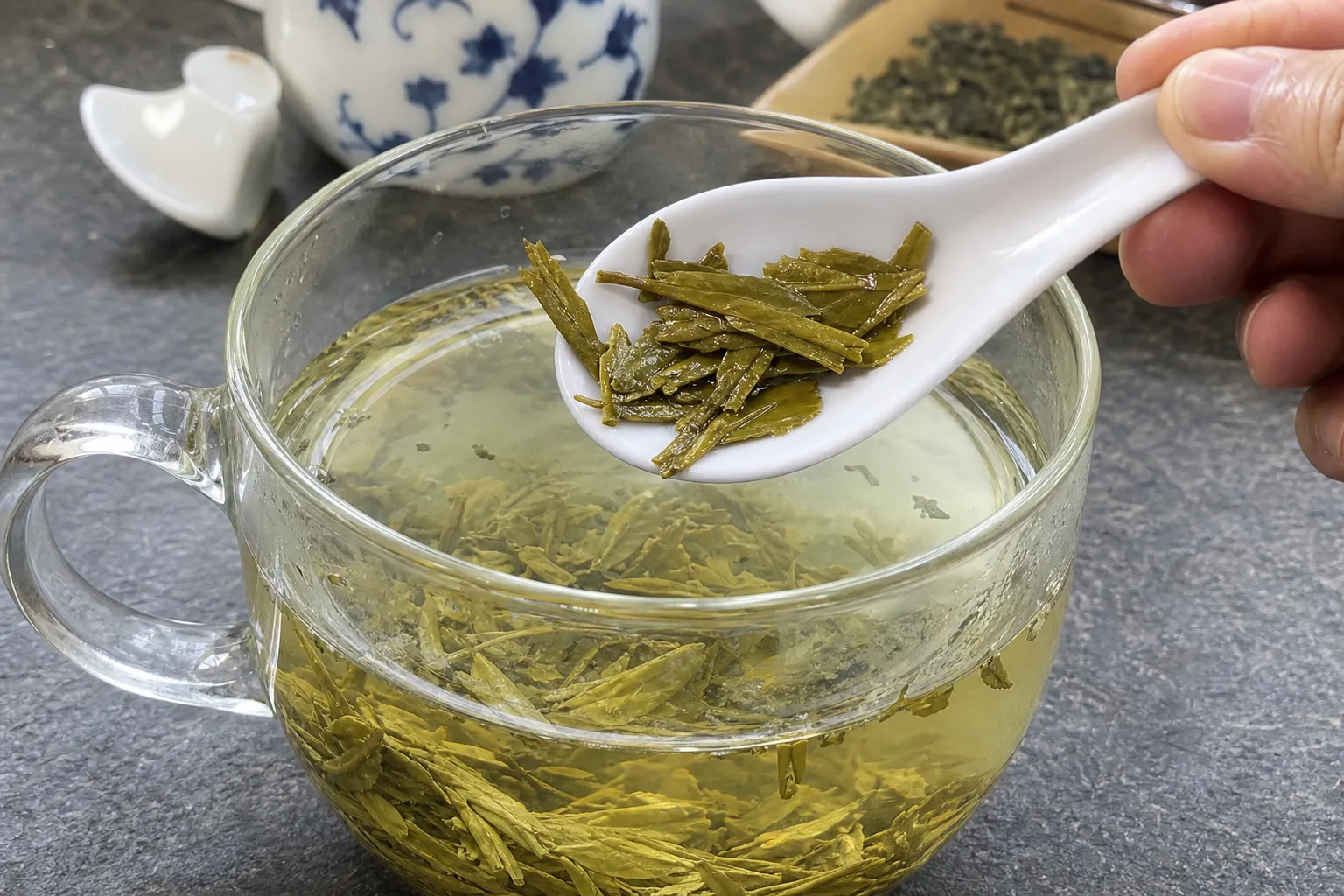 Infused Dragon Well leaves in a cup showing softened flat pieces and broken fragments after steeping