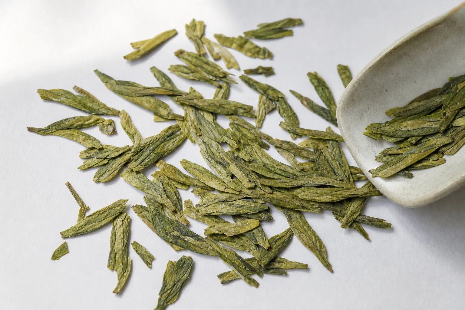 Flat Dragon Well tea leaves spread out to show blade-like shape, coherent color, and limited dust